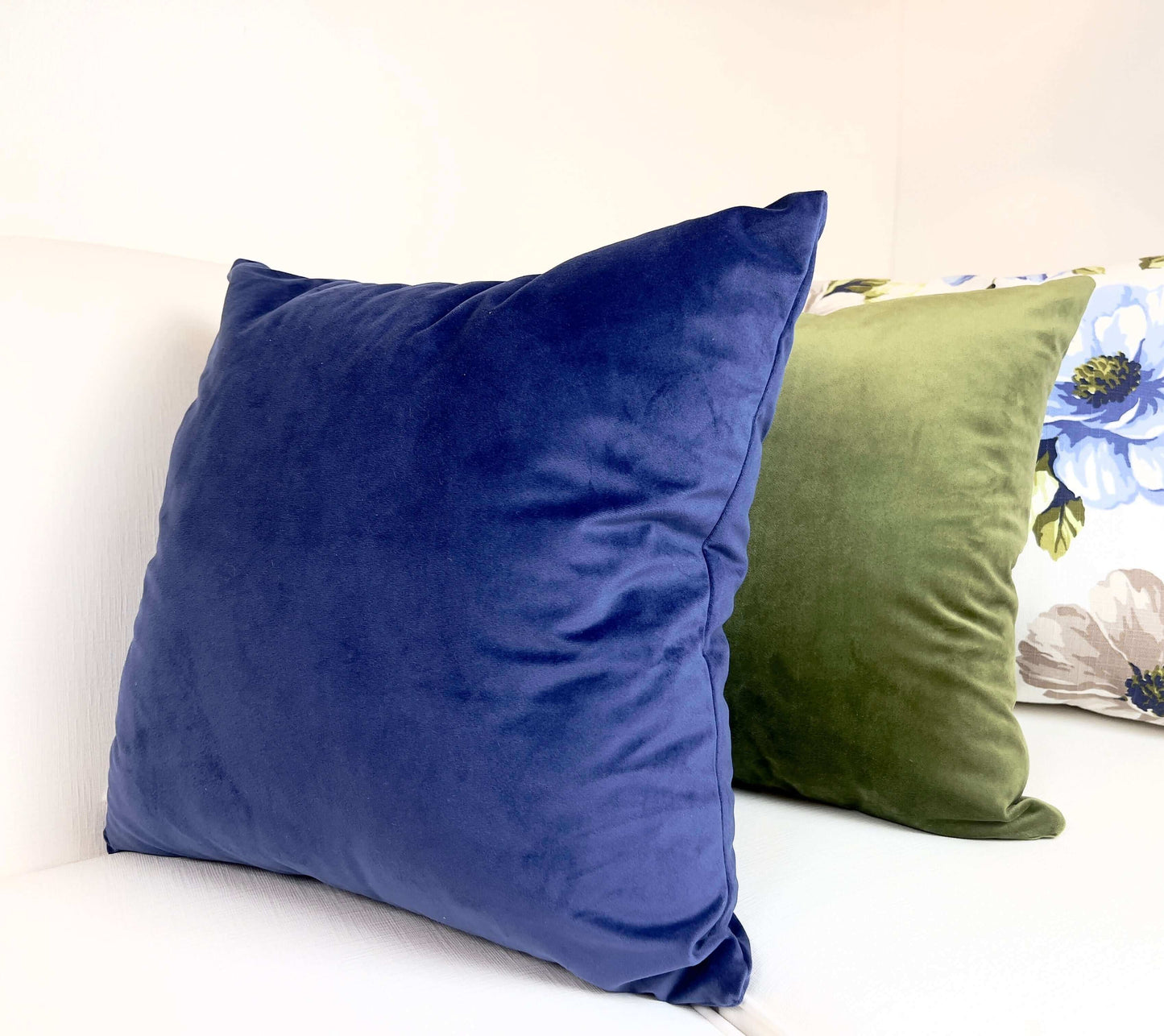 Luxury Velvet Pillow Cover in Navy Blue with an olive green pillow and a floral pillow on a white sofa