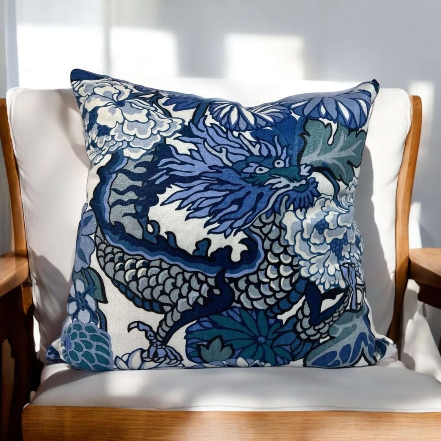 Schumacher Chiang Mai Dragon Print Linen Pillow Cover on a light wood armchair