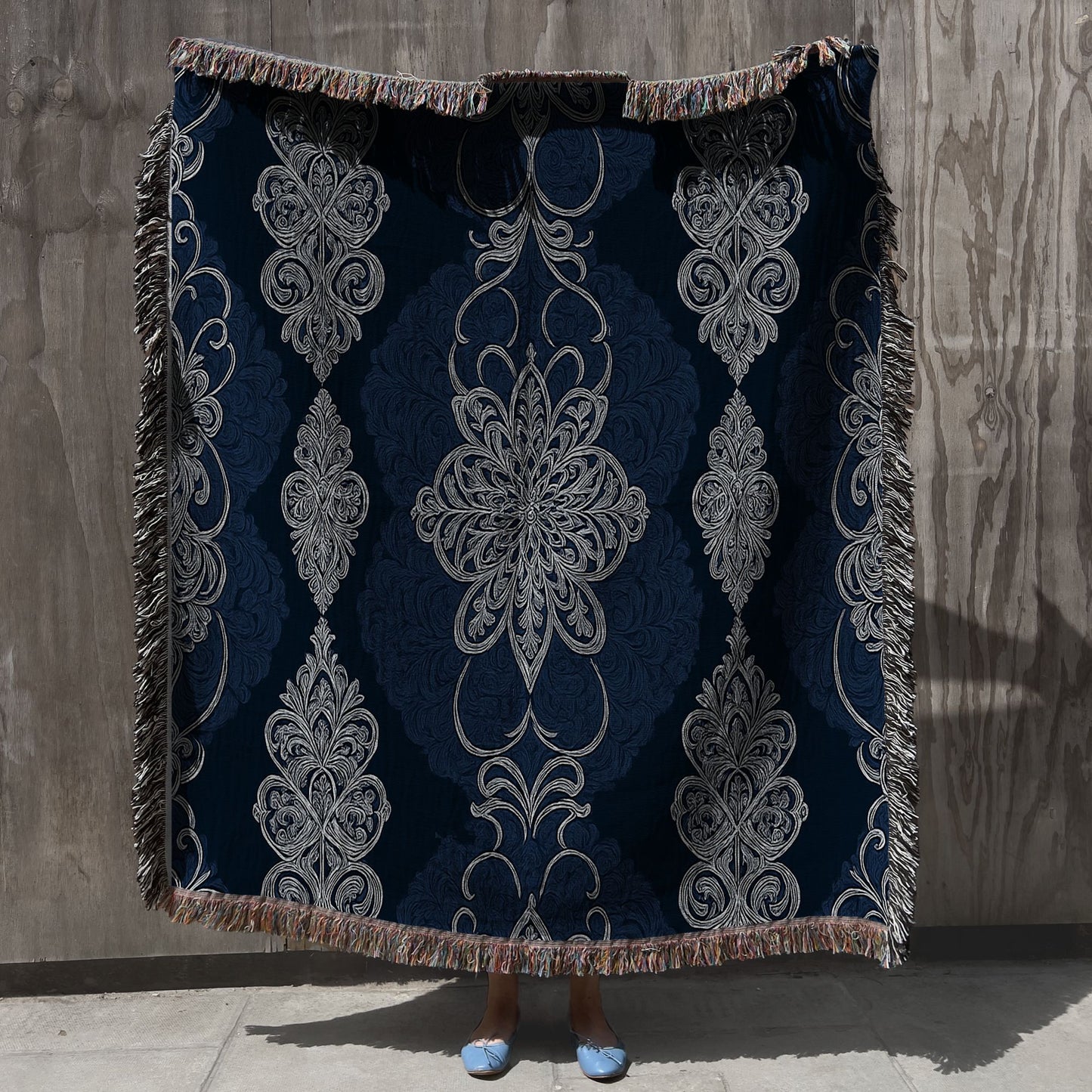 Decorative throw blanket with intricate patterns on a textured wall background