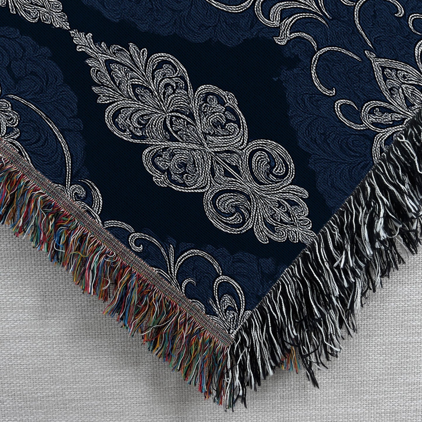 Embroidered fabric with intricate patterns and fringes on a textured background