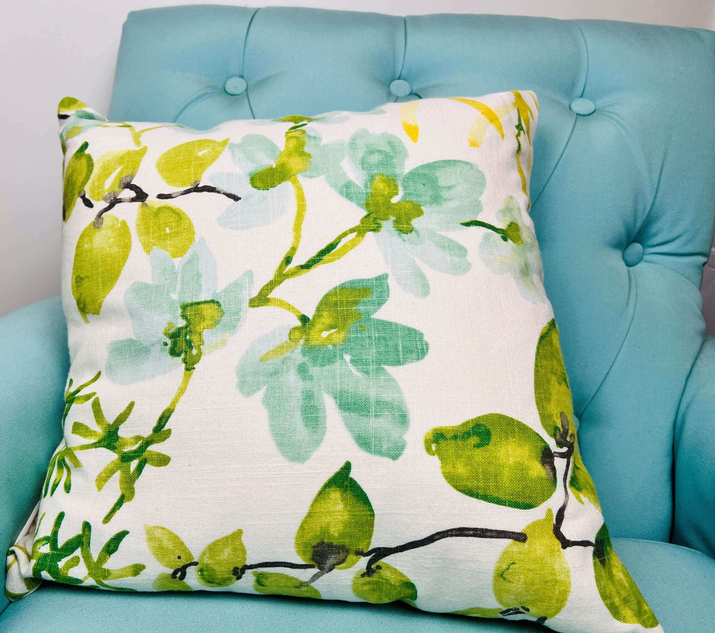 Braemore Gazebo Designer Linen floral pillow cover in color citrus resting on an aqua armchair