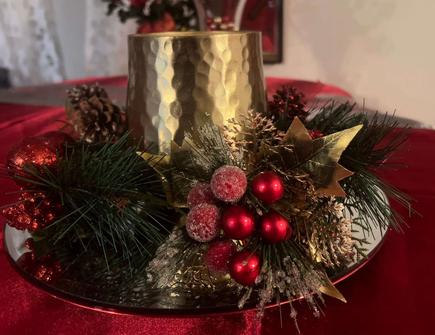 Decorative arrangement with a Gold Jumbo Soy Candle in Cranberry Chutney, red berries, and greenery on a red surface.