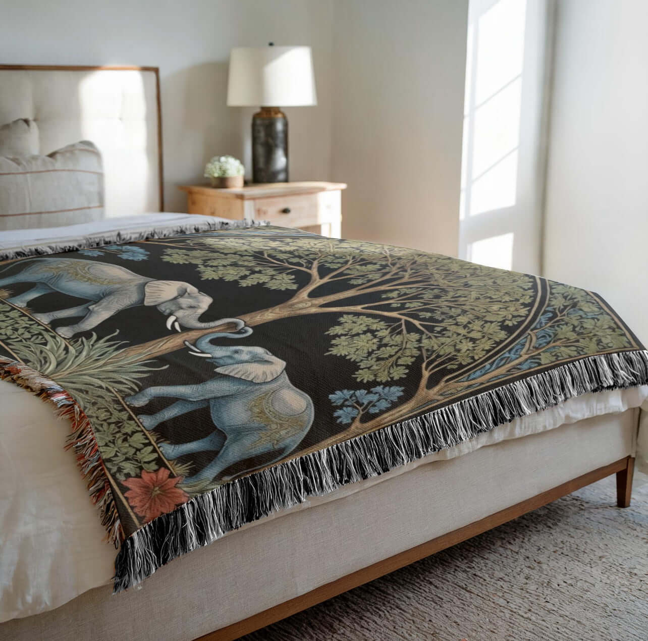 Two elephants on a woven fringed blanket spread out on a bed.