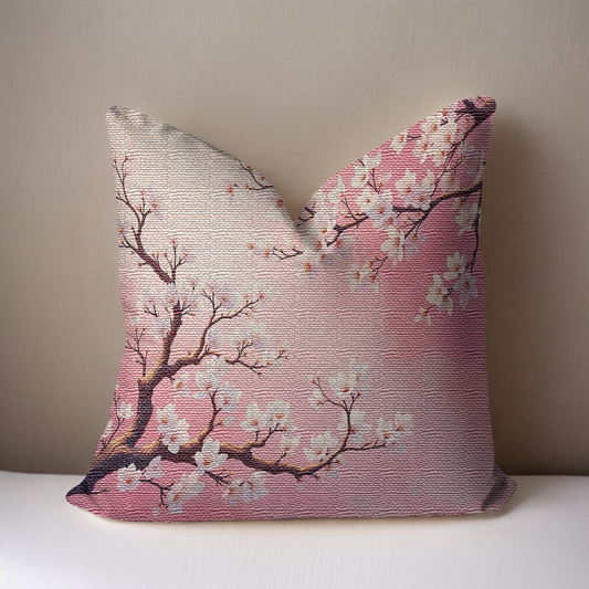 Pink Almond Blossom Woven Pillow on a white surface against a taupe background.
