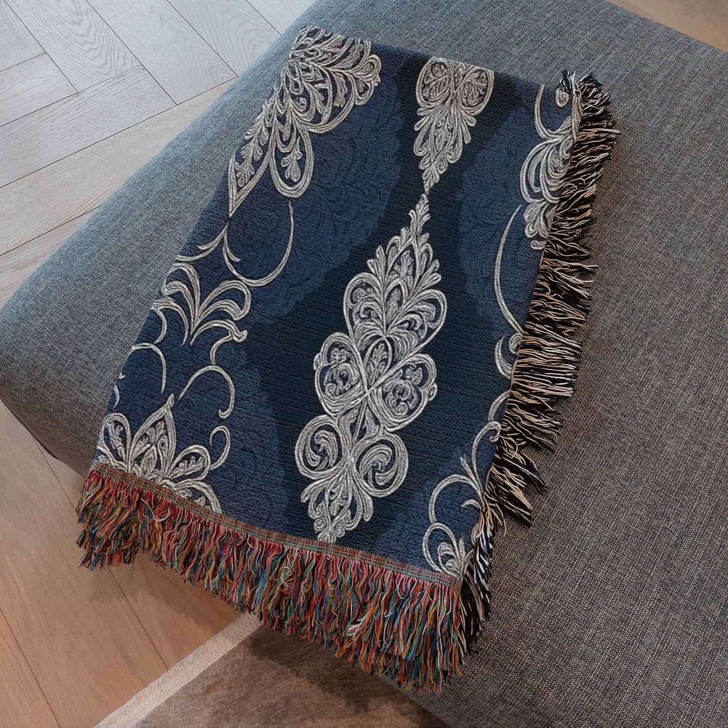Decorative navy blanket with fringes folded on a stool.