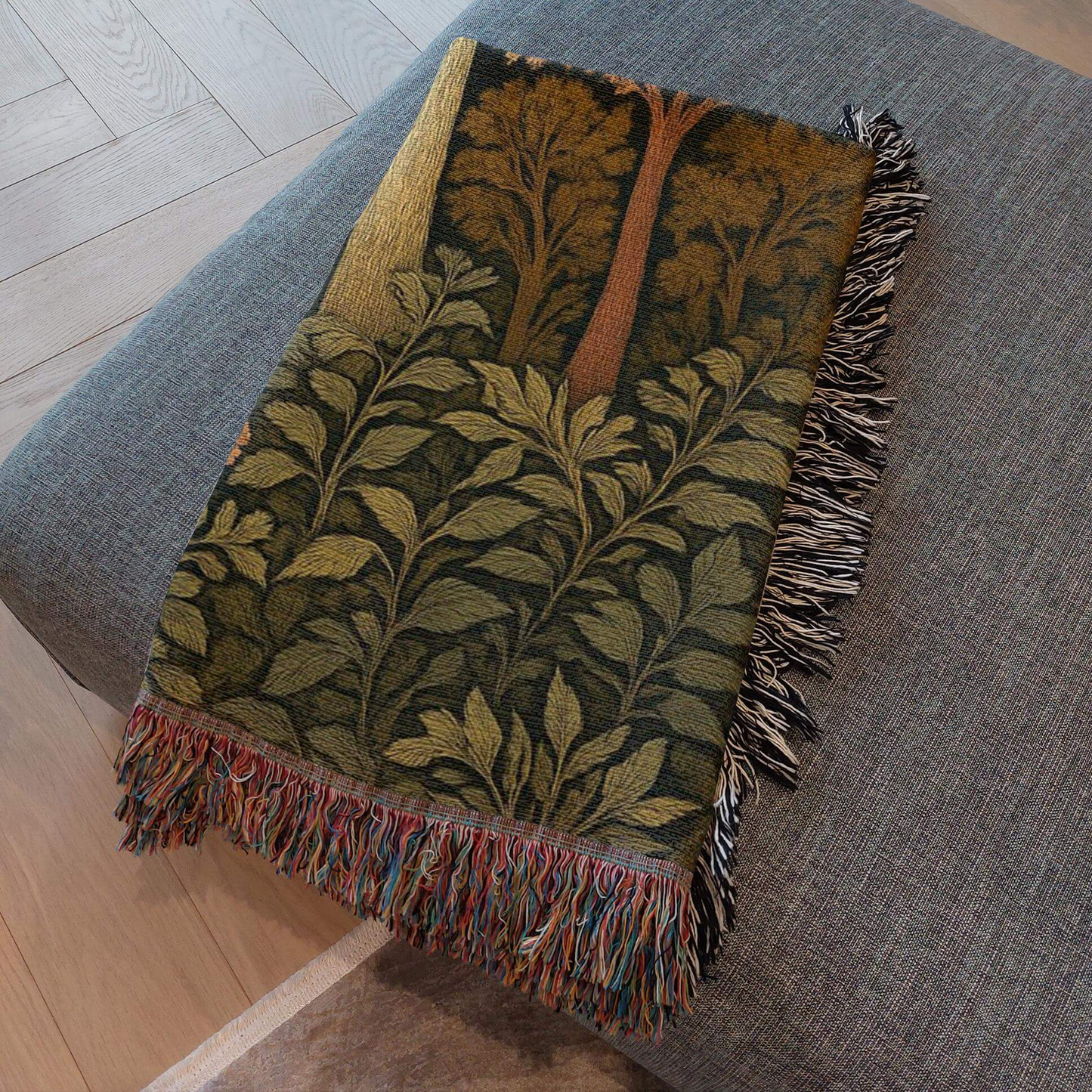 Autumn Forest Woven Blanket with Fringes draped on a gray sofa showcasing intricate woven details and vibrant fall colors.