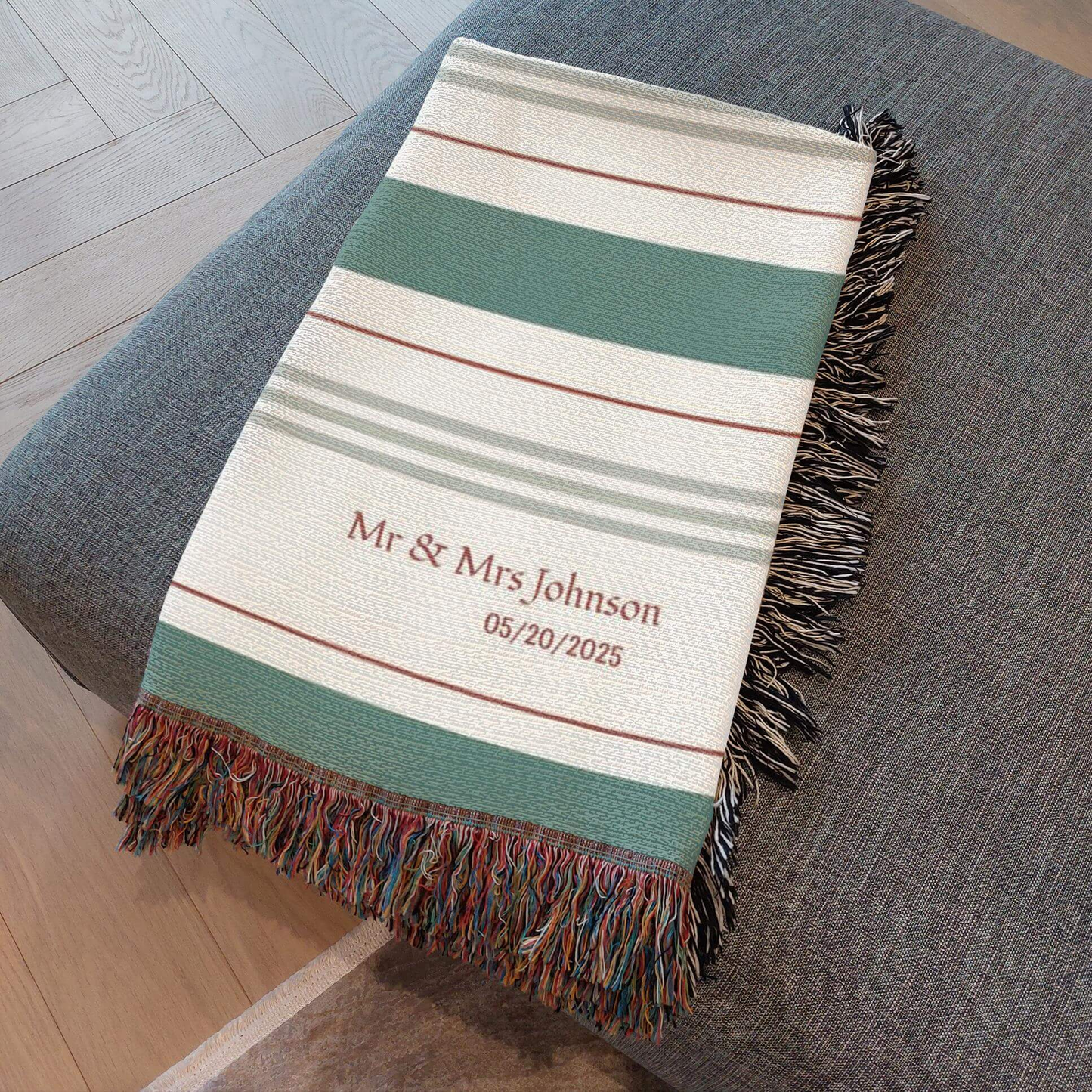 Personalized Striped Woven Blanket folded and resting on an ottoman.

