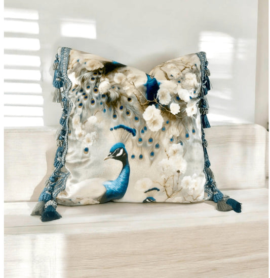 White Peacock Velvet Pillow Cover with Tassel Trim on a light wood shelf.