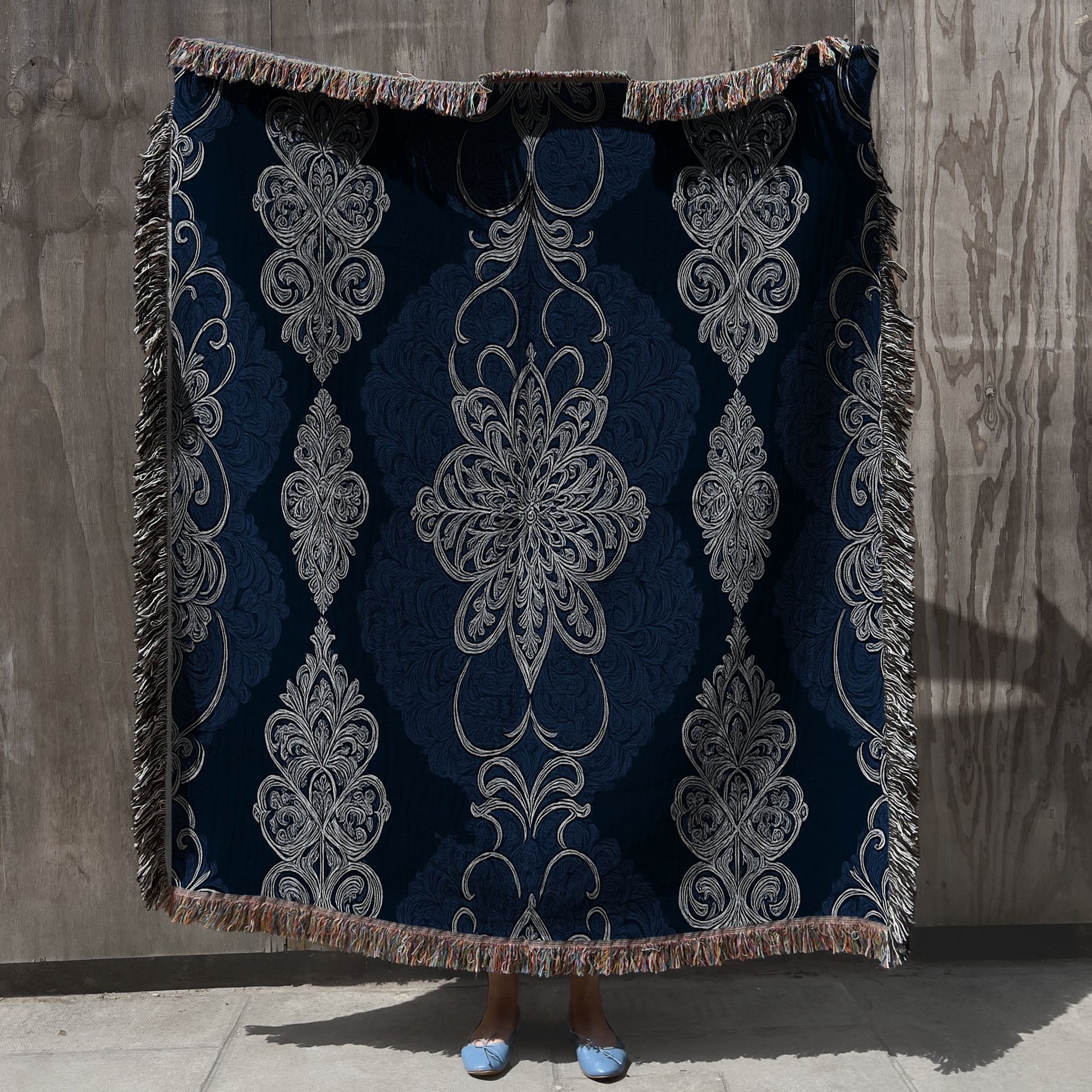 Decorative throw blanket with intricate patterns on a textured wall background