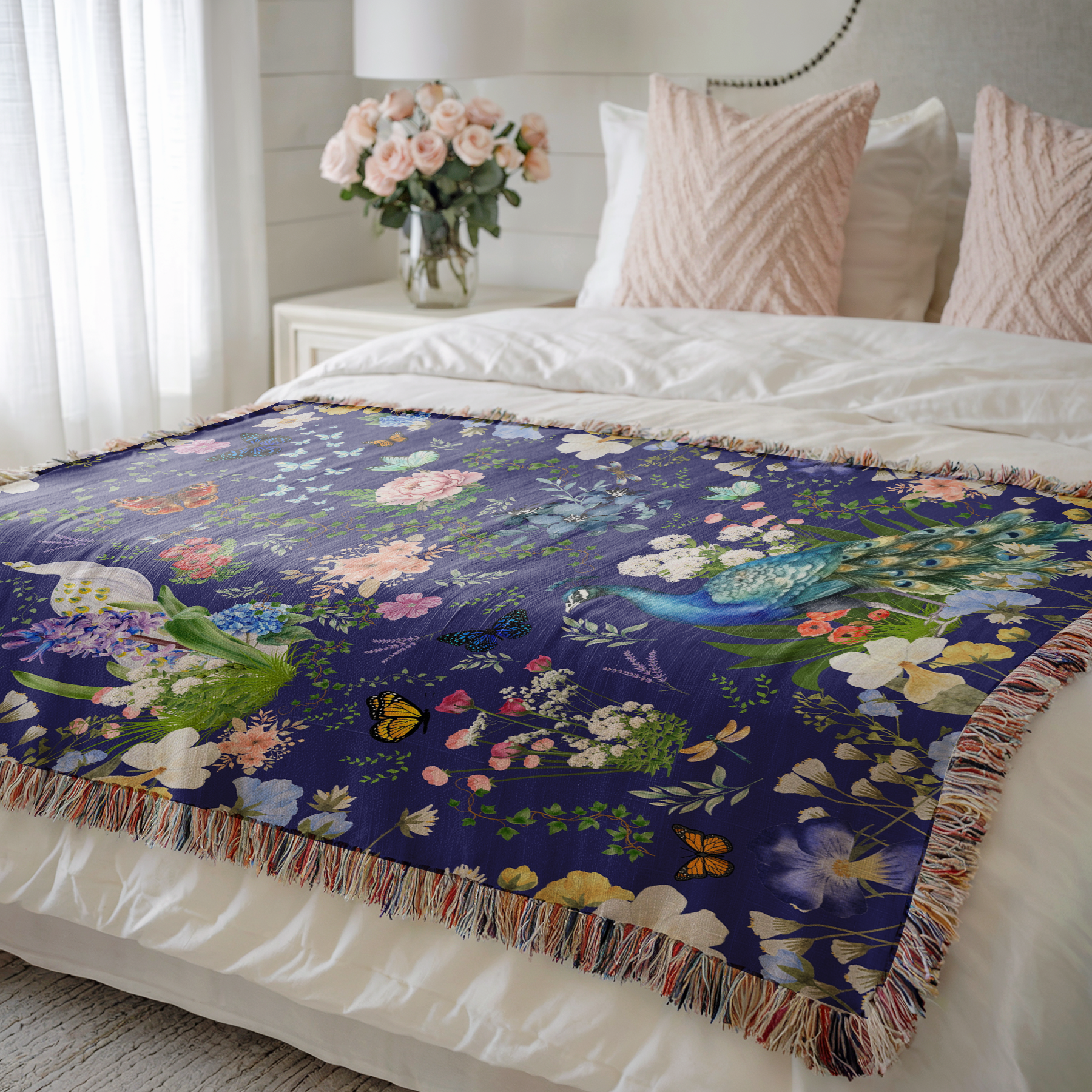 Blue Peacock Floral Woven Blanket with Fringes on a bed with pink pillows and a window near 