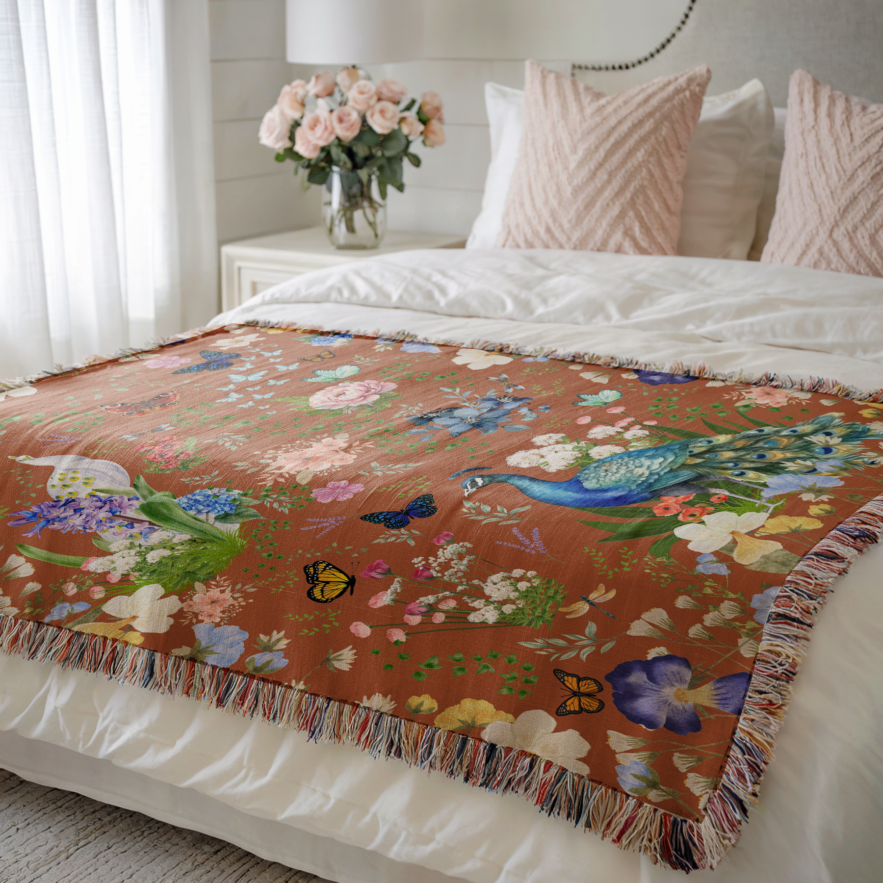 Cinnamon Brown Peacock Floral Woven Blanket draped on a bed with pink pillows