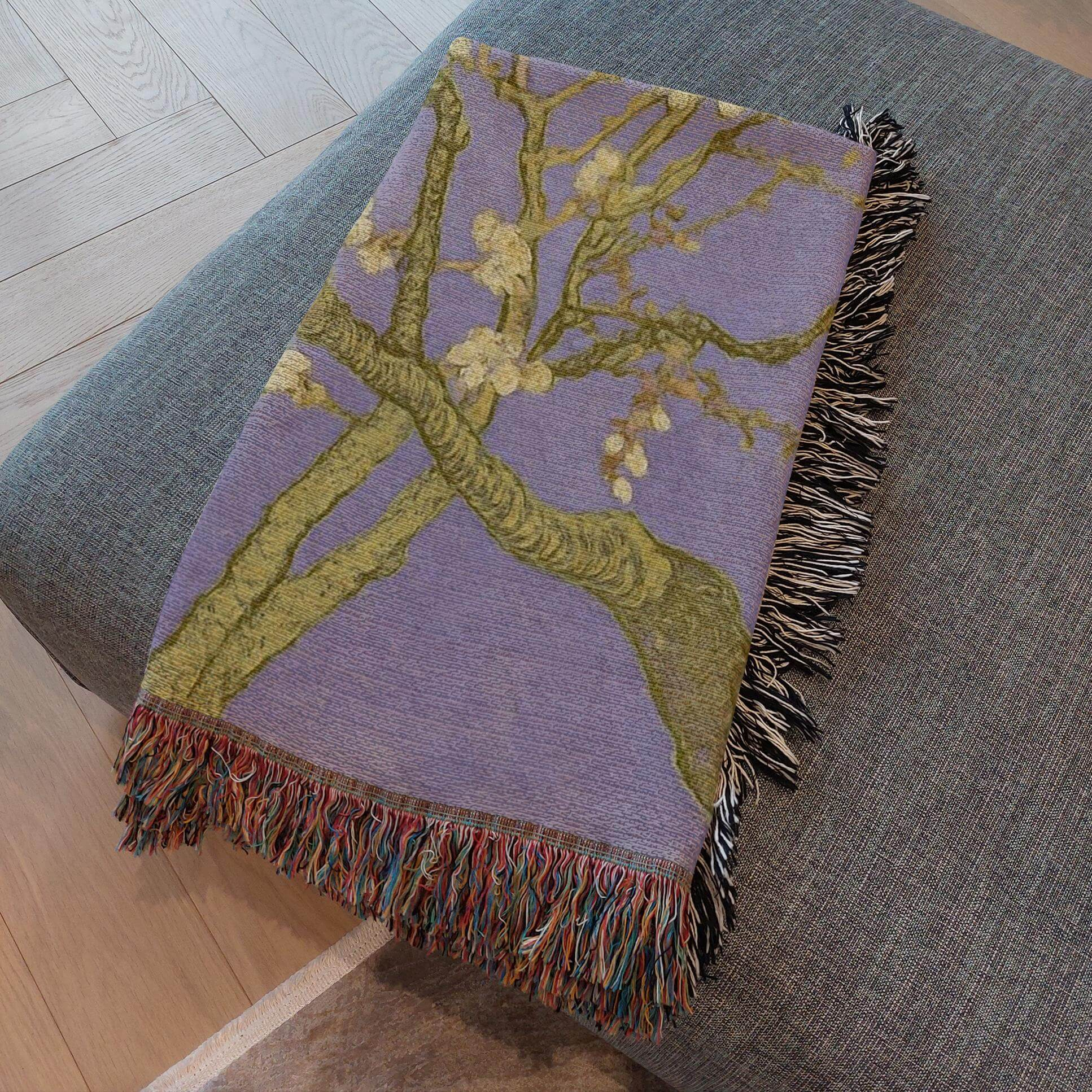 Lavender Almond Blossom Woven Blanket showcasing delicate ivory blossoms on a lavender background with fringe detail.