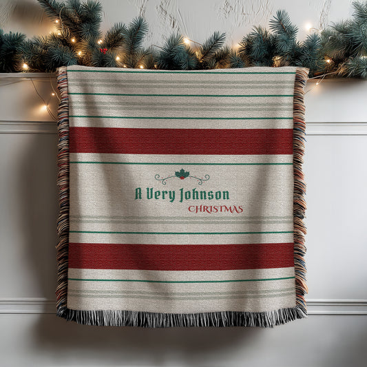 Personalized Dark Red Woven Striped Christmas Blanket hanging from a shelf, with Christmas garland on the shelf