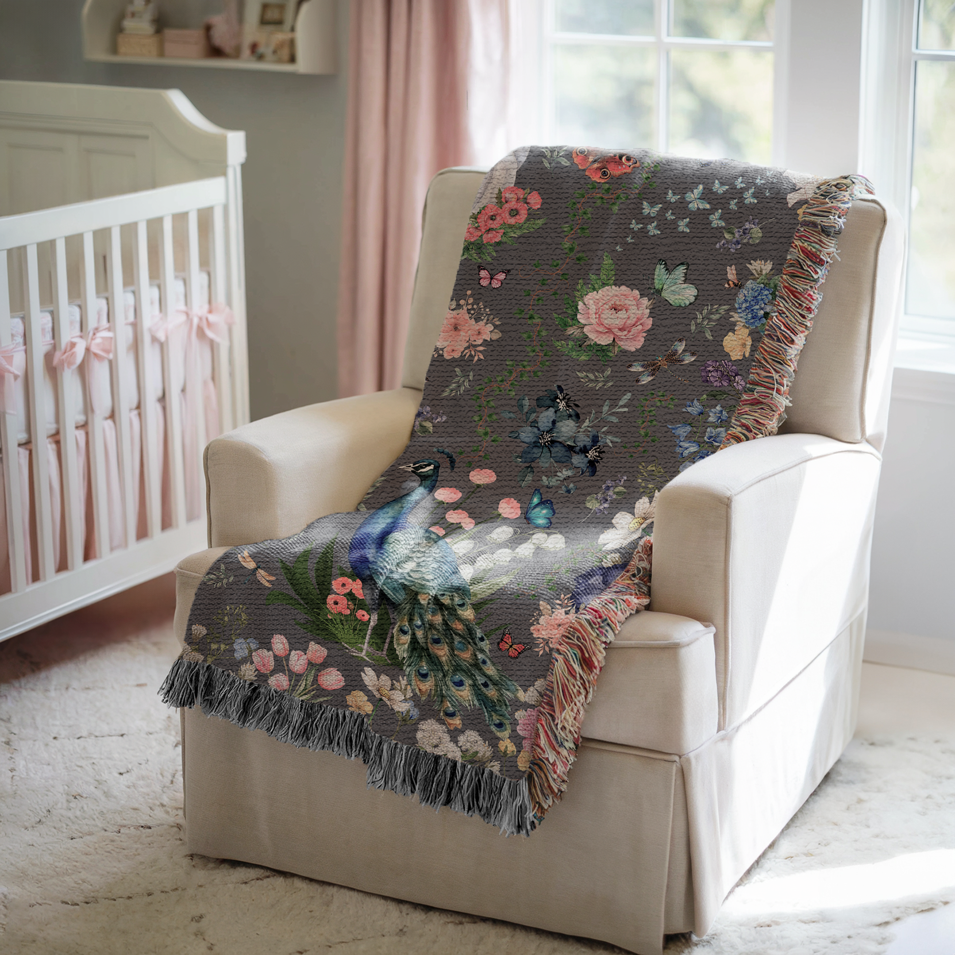 Dark Gray Peacock Floral Woven Blanket with Fringes on an off white armchair in a baby nursery