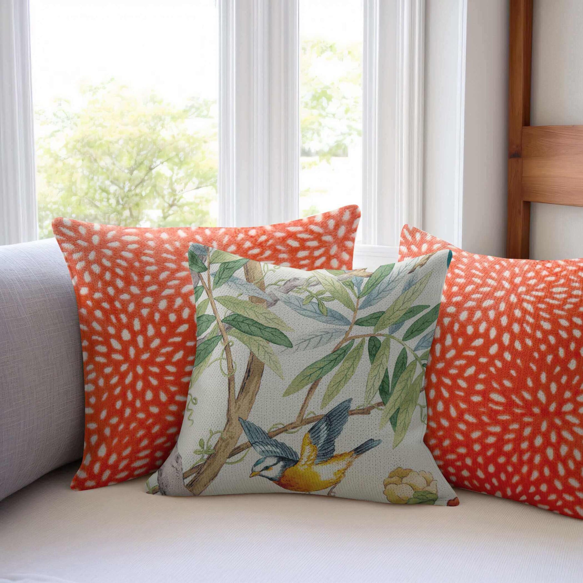 Close up of two Sun Coral Cut Velvet Pillow Covers and one floral pillow on a white  sofa.