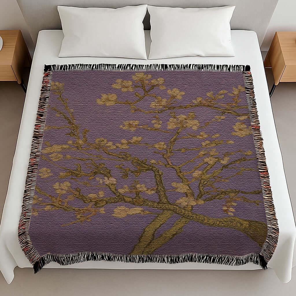 Lavender Almond Blossom Woven Blanket displayed on a bed, featuring delicate ivory blossoms against a lavender background.