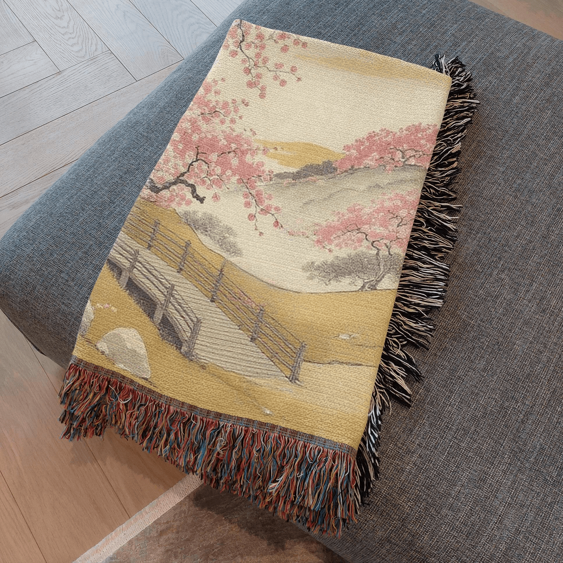 Cherry Blossom Tree Woven Blanket Tapestry folded and resting on an ottoman.