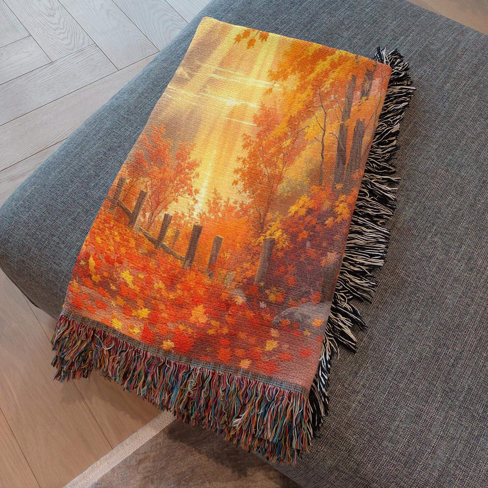 Close-up of Autumn Day Woven Blanket Tapestry folded and resting on gray a ottoman